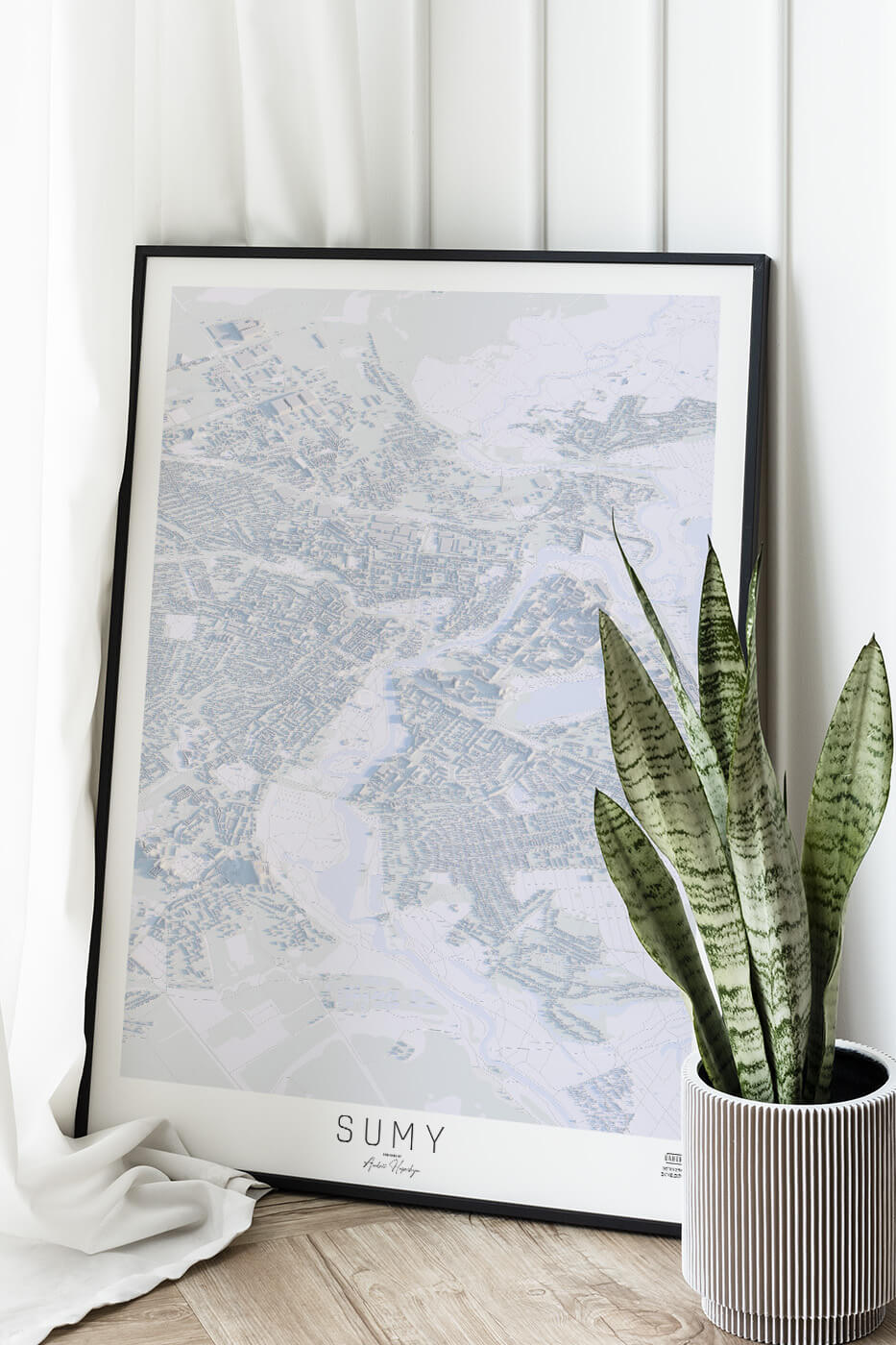 Картина міста Суми в рамці на фоні стіни